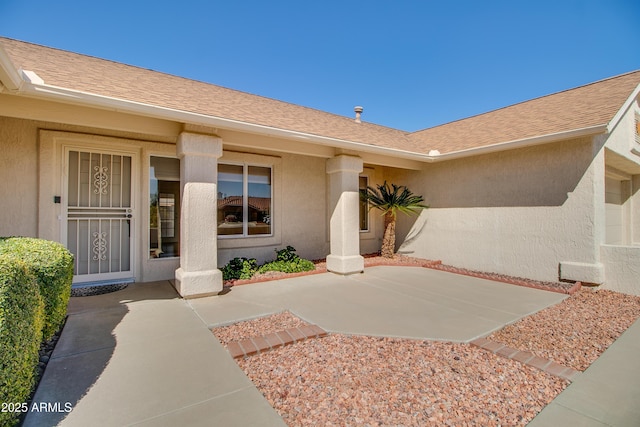 property entrance featuring roof with shingles and stucco siding