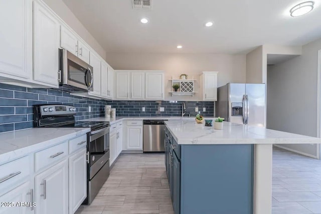 29891 N Desert Angel Dr, San Tan Valley, AZ 85143 - kitchen with stainless steel appliances, a sink, open shelves, white cabinets, and tasteful backsplash
