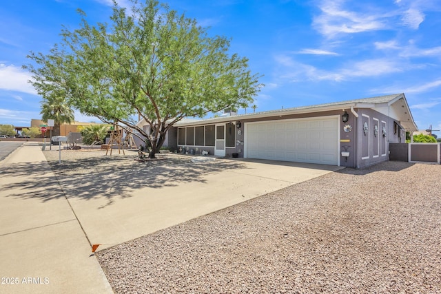 ranch-style home with a sunroom, a garage, stucco siding, and concrete driveway