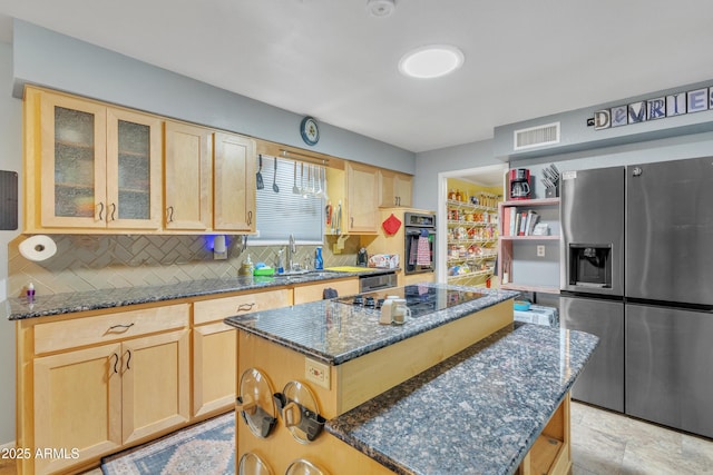 kitchen with light brown cabinetry, a sink, backsplash, visible vents, and black appliances