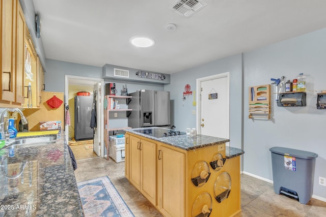 kitchen featuring stainless steel fridge, a sink, black electric stovetop, and visible vents