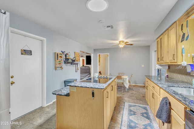 kitchen featuring light brown cabinetry, ceiling fan, a kitchen island, and black electric stovetop