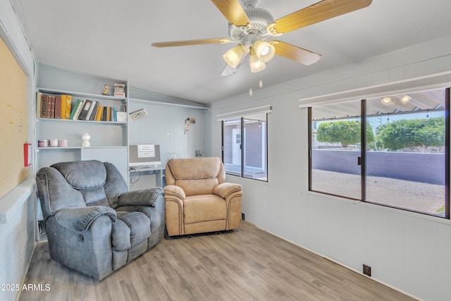 living area with ceiling fan, vaulted ceiling, plenty of natural light, and wood finished floors