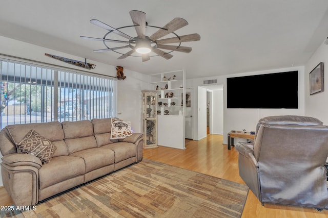 living room featuring a ceiling fan, visible vents, and wood finished floors