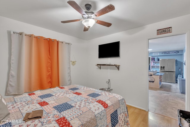 bedroom with light wood-style floors, ceiling fan, and stainless steel fridge with ice dispenser