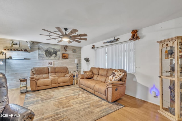 living area featuring baseboards, ceiling fan, and wood finished floors