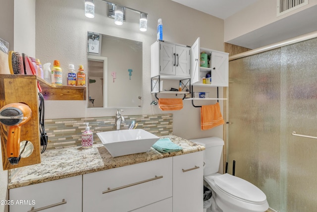 bathroom featuring visible vents, tasteful backsplash, a shower stall, vanity, and toilet
