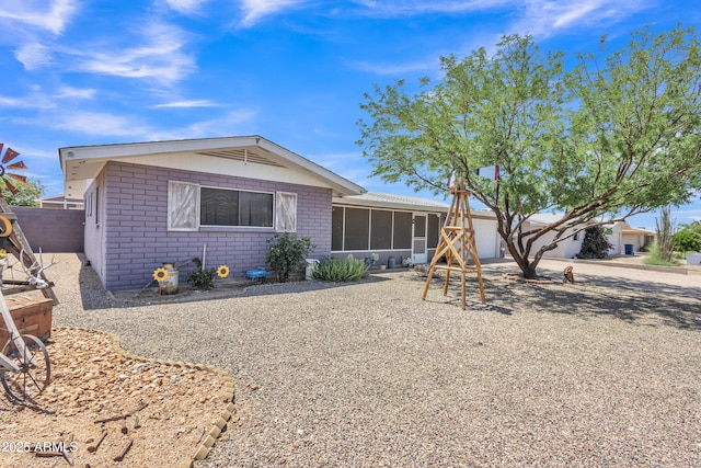 view of front of home featuring fence, an attached garage, a sunroom, and brick siding