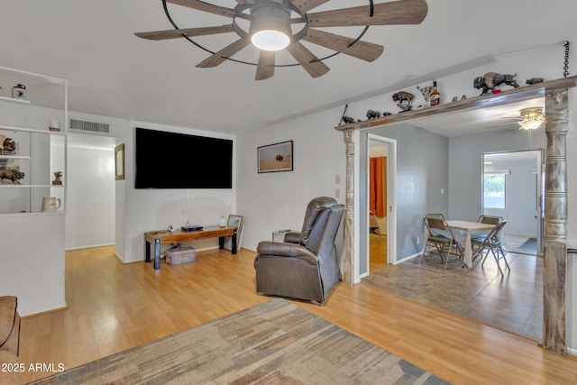 living area with baseboards, ceiling fan, wood finished floors, and visible vents