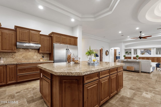 kitchen featuring decorative backsplash, stainless steel built in refrigerator, a center island, and ceiling fan