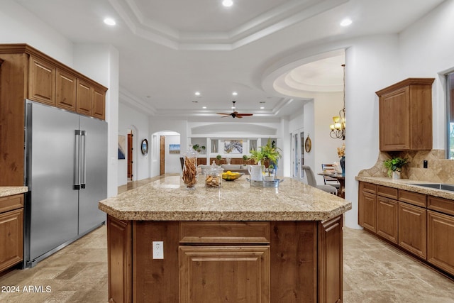 kitchen featuring a kitchen island, decorative backsplash, stainless steel built in refrigerator, and a raised ceiling