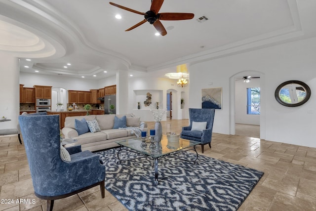 living room featuring ornamental molding, a tray ceiling, and ceiling fan with notable chandelier