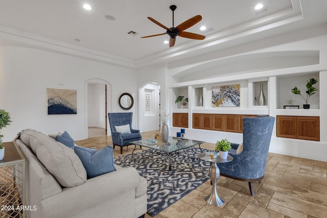 living room with a raised ceiling and ceiling fan