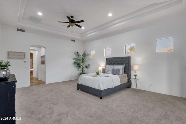 carpeted bedroom featuring a raised ceiling, a towering ceiling, and ceiling fan