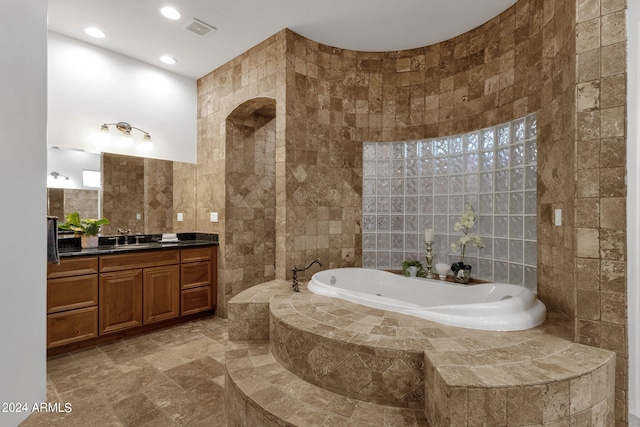 bathroom with vanity, tile walls, and tiled tub