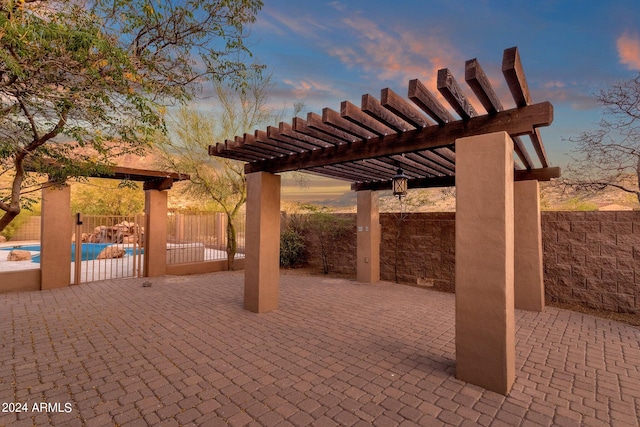 patio terrace at dusk featuring a pergola and a fenced in pool