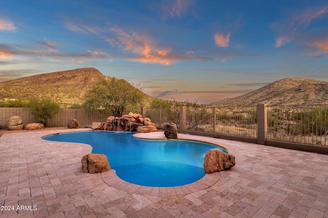 pool at dusk featuring a patio area and a mountain view