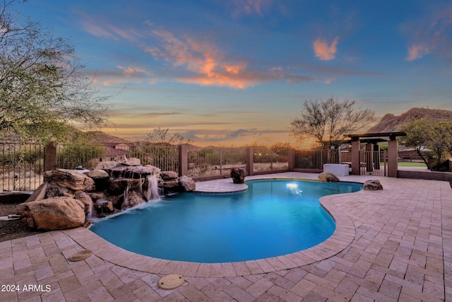 pool at dusk featuring a patio and pool water feature