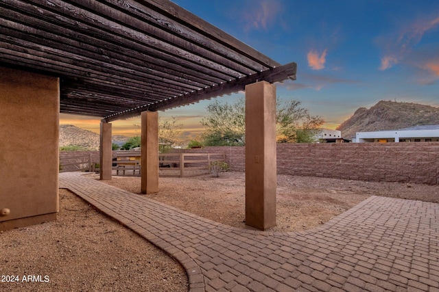 patio terrace at dusk featuring a mountain view and a pergola