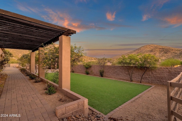 yard at dusk featuring a mountain view and a pergola