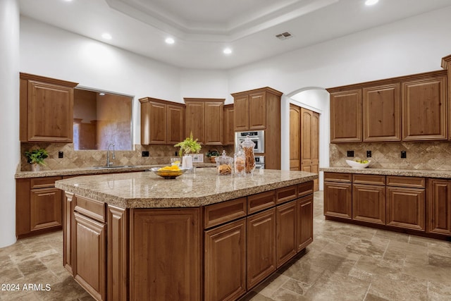 kitchen featuring sink, a kitchen island, decorative backsplash, and oven