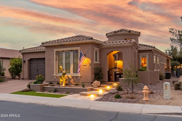 mediterranean / spanish home with driveway, a tile roof, a garage, and stucco siding