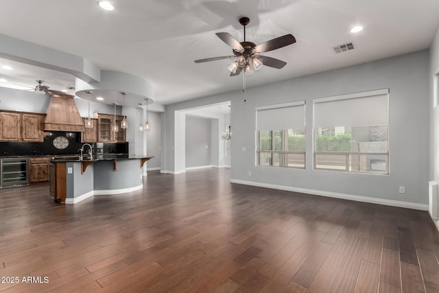 1407 E Artemis Trl, San Tan Valley, AZ 85140 - kitchen featuring visible vents, ceiling fan with notable chandelier, dark countertops, wine cooler, and custom exhaust hood
