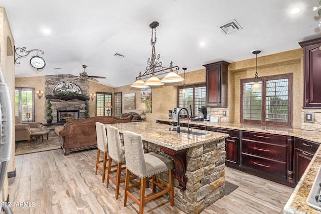 kitchen featuring vaulted ceiling, a kitchen bar, sink, and light hardwood / wood-style flooring