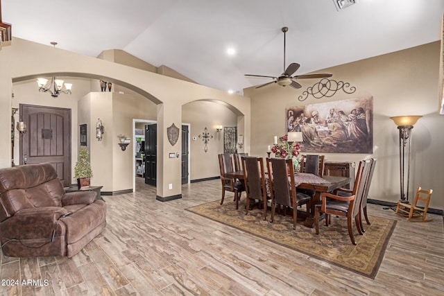 dining space featuring ceiling fan with notable chandelier, vaulted ceiling, and light hardwood / wood-style flooring