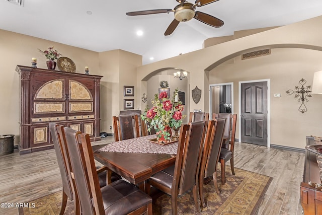 dining space with lofted ceiling, ceiling fan with notable chandelier, and light wood-type flooring