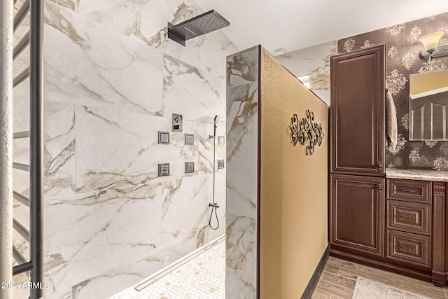 bathroom with a tile shower, vanity, and hardwood / wood-style floors