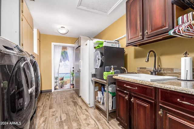 laundry room featuring washer and dryer, cabinets, light wood-type flooring, and sink