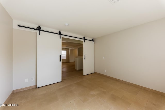 unfurnished room featuring a barn door and baseboards