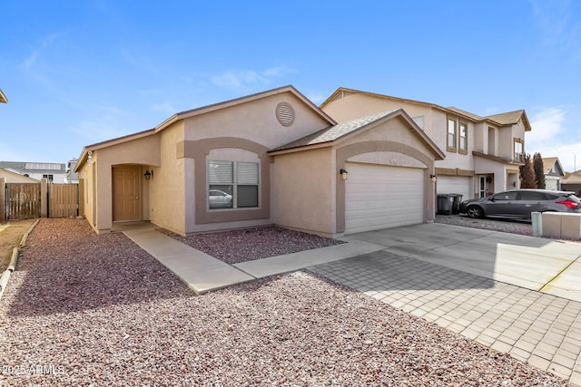 view of front of property featuring an attached garage, fence, driveway, and stucco siding