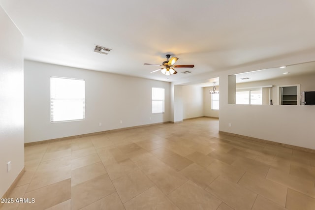 unfurnished room with light tile patterned flooring, ceiling fan with notable chandelier, visible vents, and baseboards