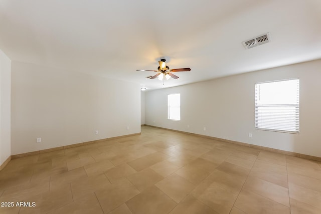 unfurnished room featuring baseboards, visible vents, and ceiling fan