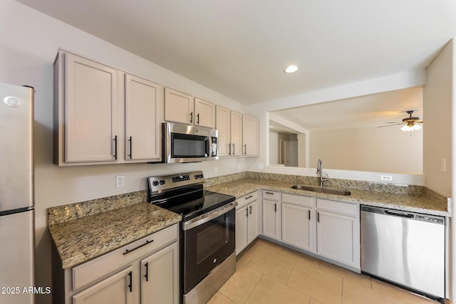 kitchen featuring light tile patterned floors, appliances with stainless steel finishes, light stone countertops, and a sink