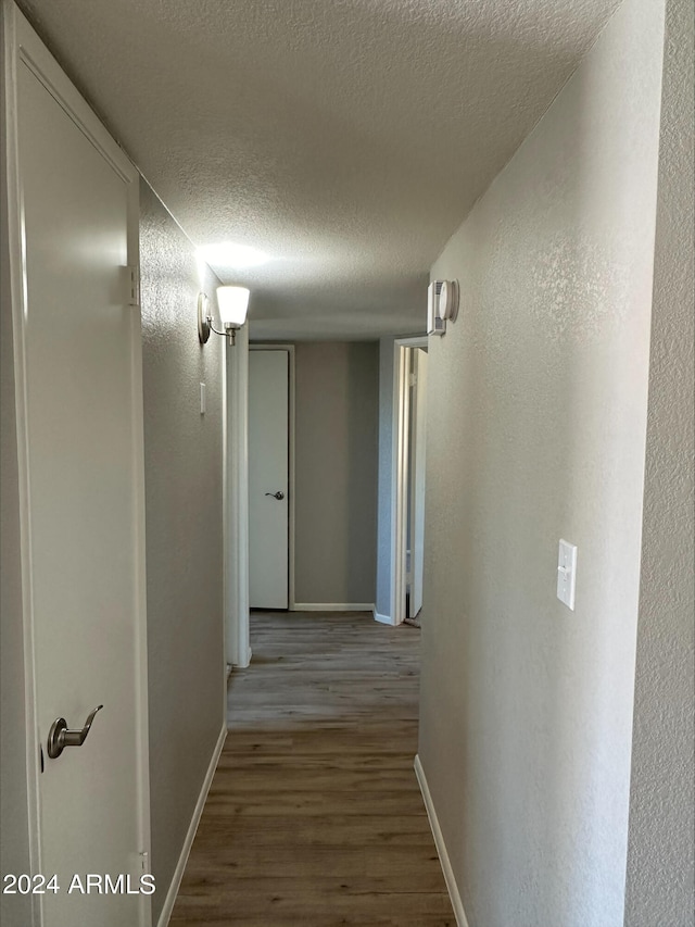 corridor featuring a textured ceiling and light hardwood / wood-style flooring