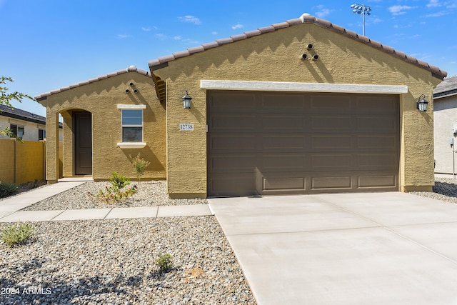 mediterranean / spanish house with an attached garage, a tiled roof, concrete driveway, and stucco siding