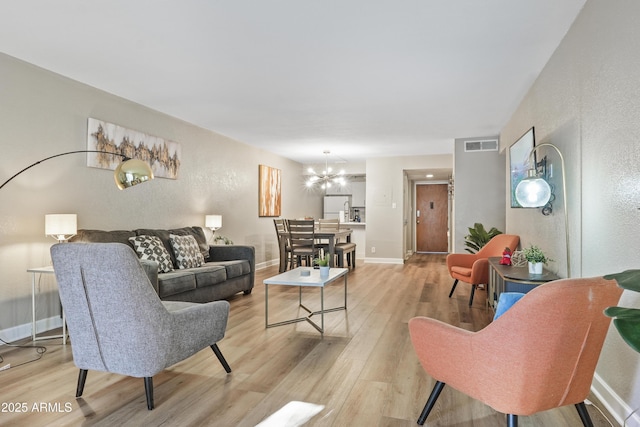 living room with a notable chandelier and light hardwood / wood-style floors