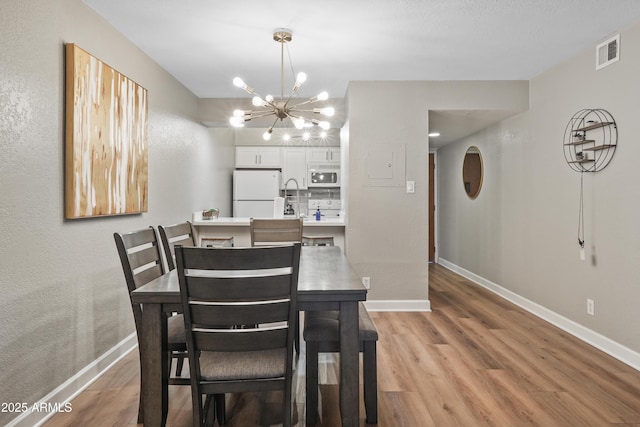 dining room with a notable chandelier and light wood-type flooring