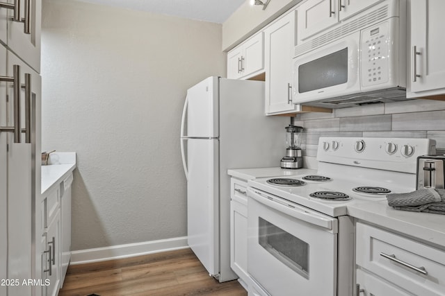 kitchen with white cabinets, white appliances, hardwood / wood-style flooring, and backsplash