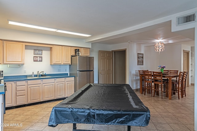 kitchen featuring stainless steel fridge, sink, light tile patterned floors, and light brown cabinets