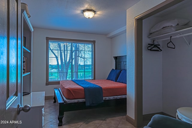 bedroom with a textured ceiling and tile patterned floors