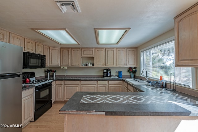 kitchen featuring black appliances, light brown cabinets, sink, light hardwood / wood-style floors, and kitchen peninsula