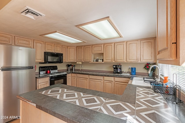 kitchen featuring light brown cabinetry, sink, stainless steel refrigerator, and white range with gas stovetop