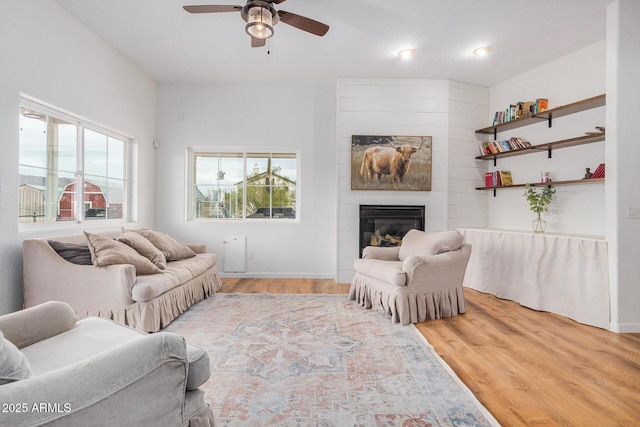 living room with light wood-style floors, a fireplace, and a ceiling fan