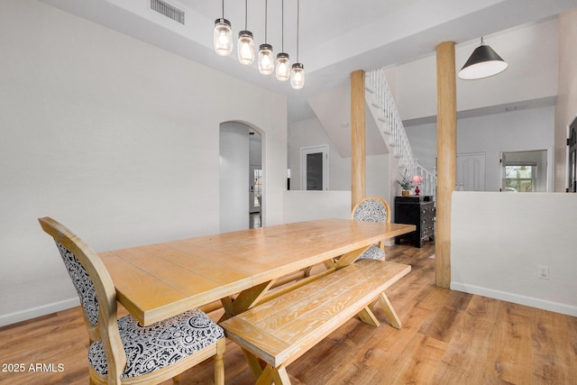 dining area with arched walkways, wood finished floors, visible vents, and baseboards