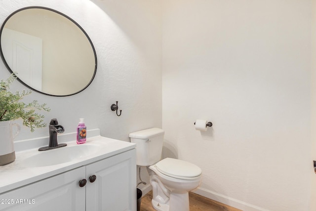 bathroom with wood finished floors, vanity, toilet, and baseboards