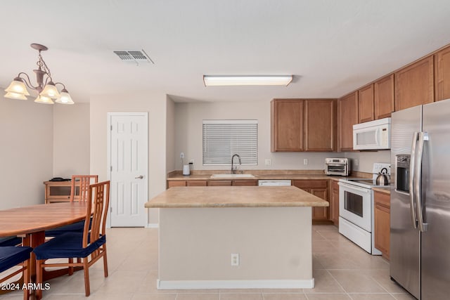 kitchen with sink, a notable chandelier, pendant lighting, white appliances, and a kitchen island